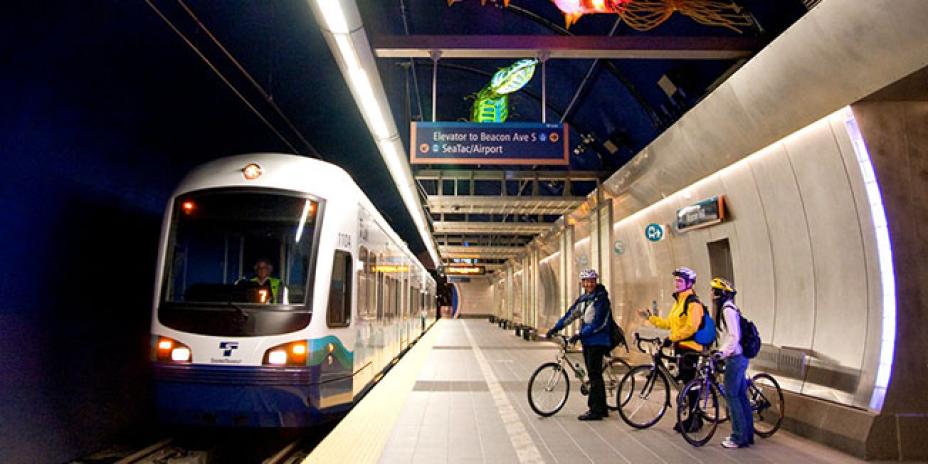 Bicyclists wait to board an incoming Link light rail train.